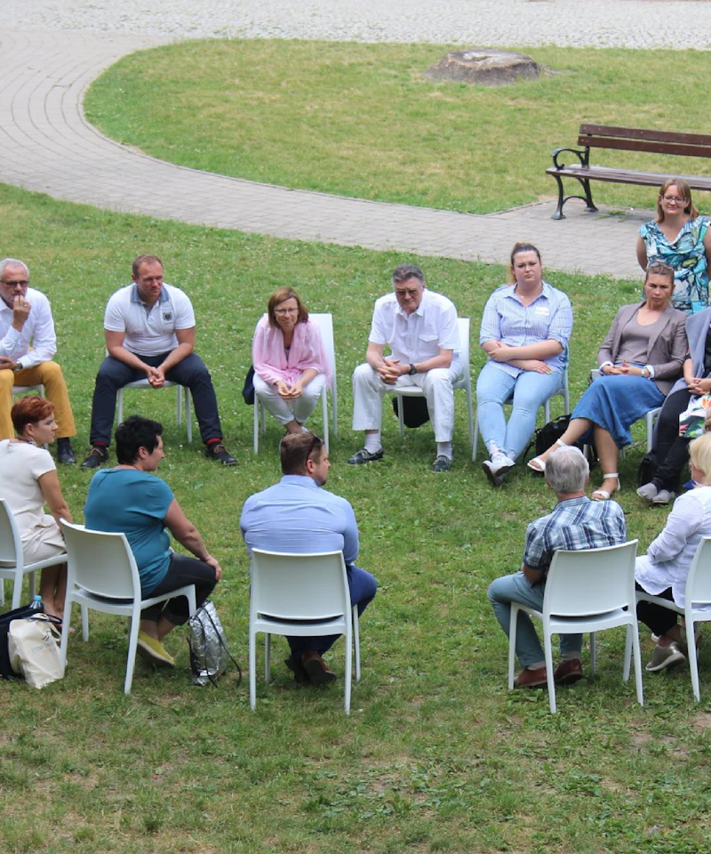 Cercle de chaises dans l'herbe, participants réunis en plein air