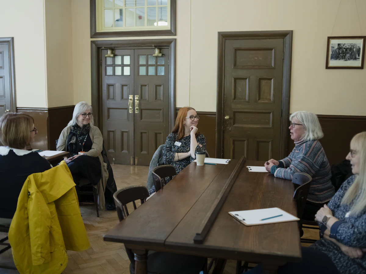 Réunion autour d'une table en bois dans une salle paroissiale